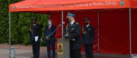 Zdjęcie przedstawia Świętokrzyskiego Komendanta Wojewódzkiego PSP podczas przemowy, w tle trybuna honorowa z zaproszonymi gośćmi.