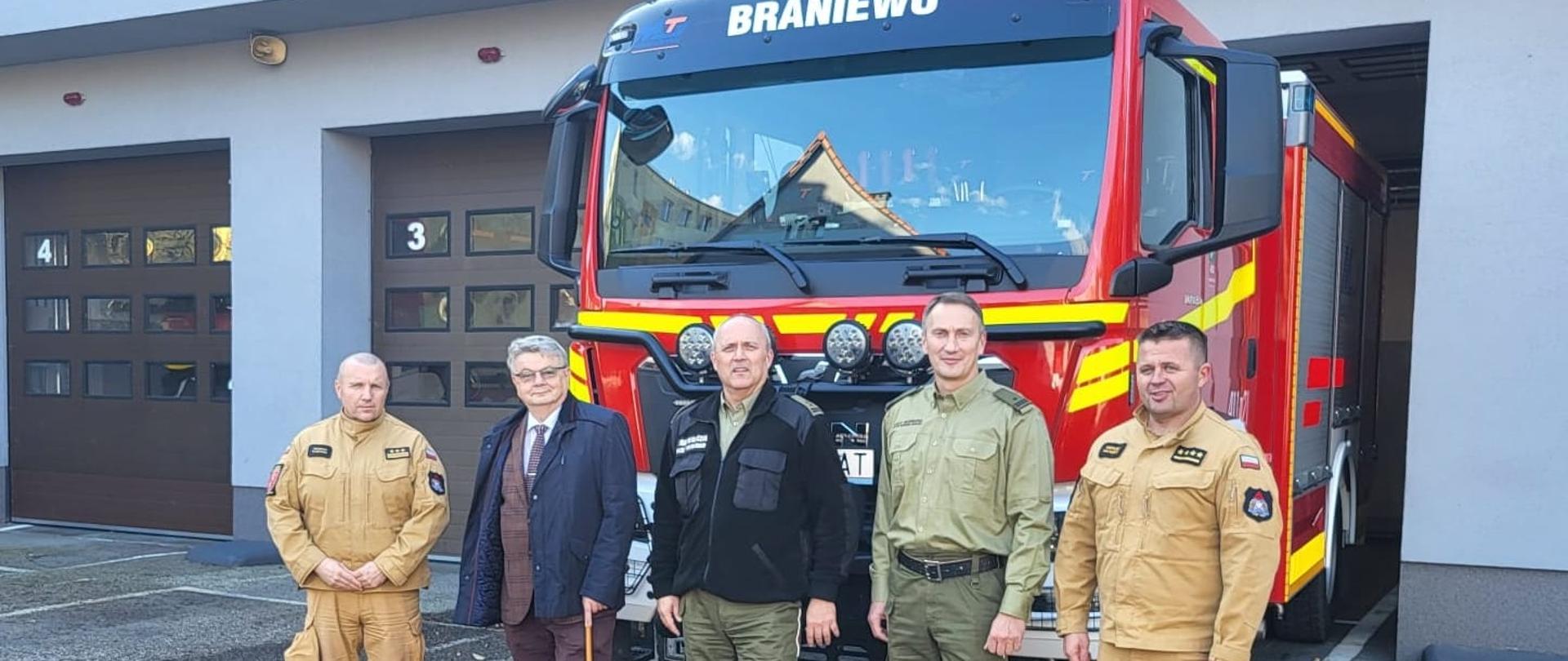 Na tle dużego samochodu strażackiego stoją od lewej Komendant powiatowy, starosta braniewski, komendant SG i zastępca komendanta SG oraz dowódca jednostki ratowniczo gaśniczej z Braniewa