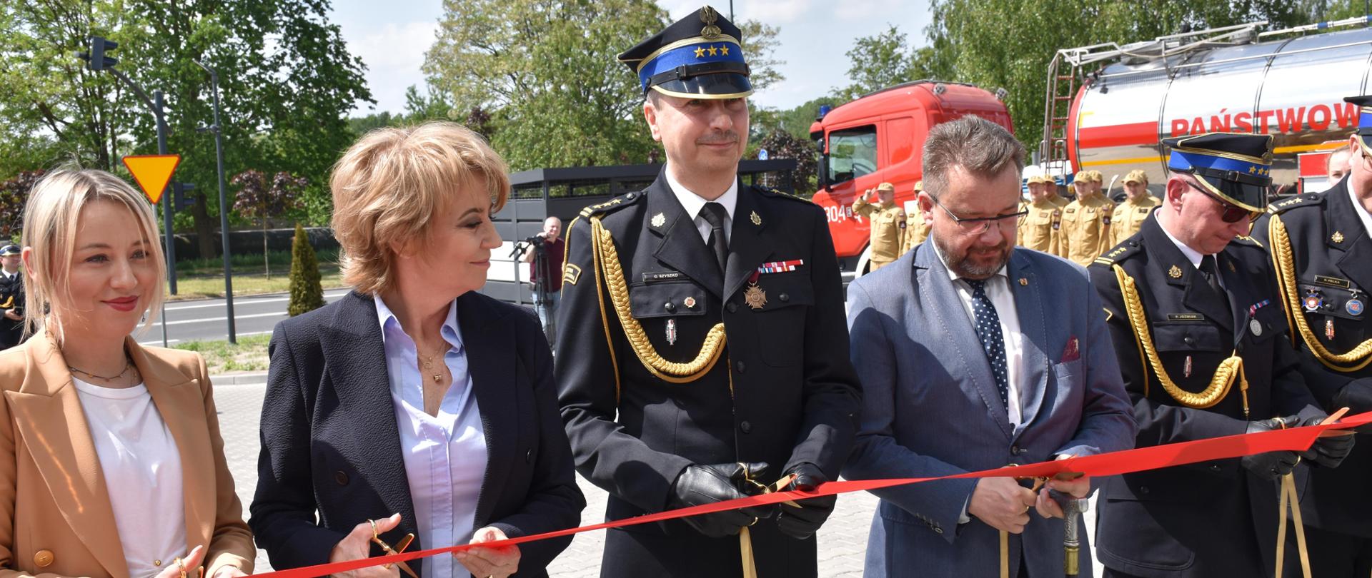 Strażacy i osoby cwyilne przecinają wstęgę