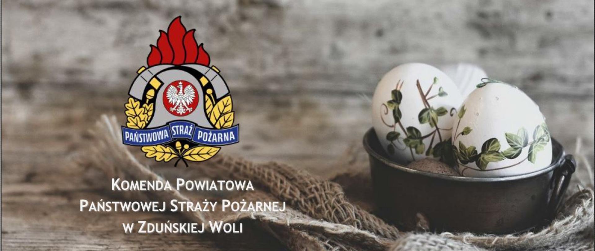 Grafika przedstawia kolorowe logo PSP z białym podpisem Komenda Powiatowa Państwowej Straży Pożarnej w Zduńskiej Woli umiejscowione z lewej strony, z prawej widoczne pisanki wielkanocne.