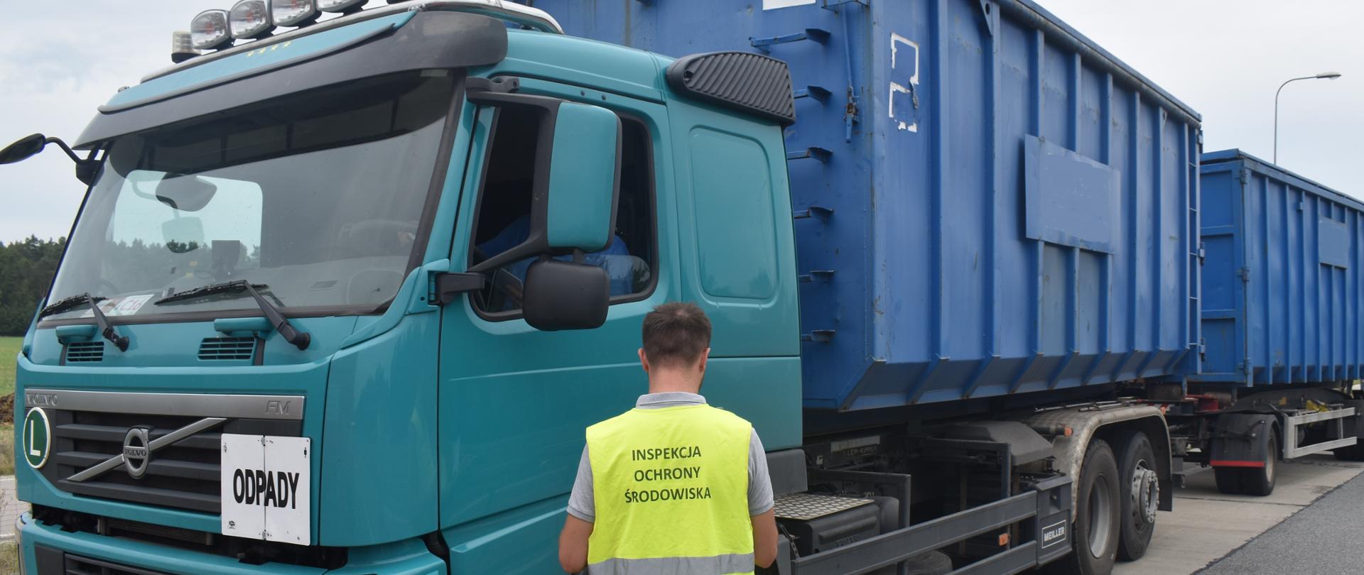 Inspektor Wojewódzkiego Inspektoratu Ochrony Środowiska w Warszawie kontroluje samochód ciężarowy.