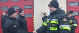 Zdjęcie przedstawia trzech strażaków podczas zmiany służby podczas wręczania awansów.