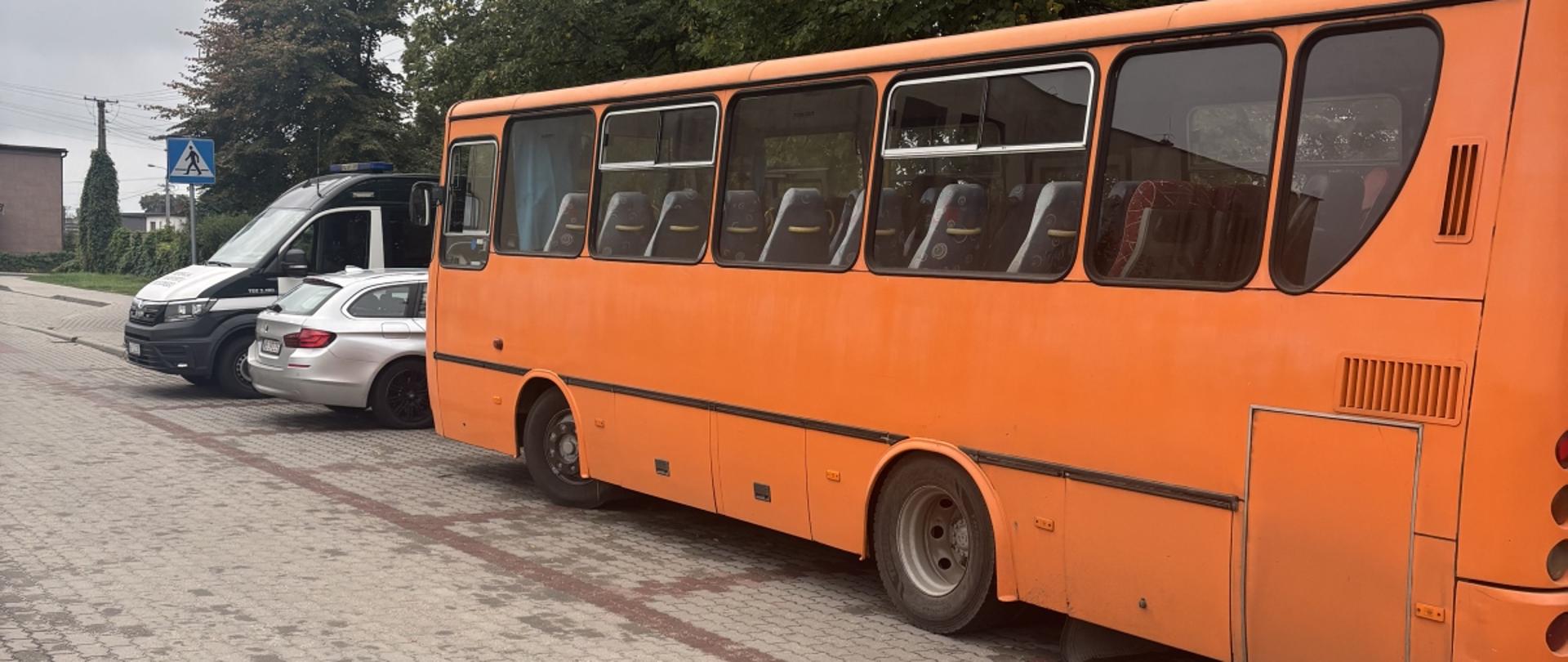 Autobus w kolorze pomarańczowym stojący na punkcie kontrolnym podczas przeprowadzania czynności kontrolnych