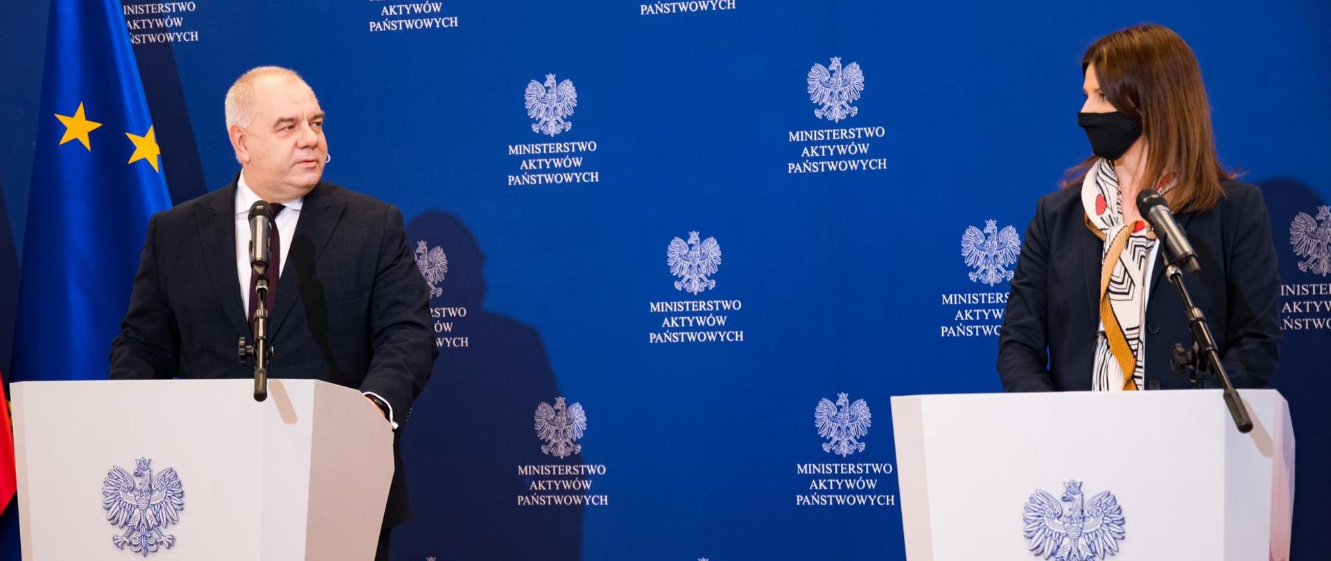 Wicepremier Jacek Sasin oraz Danuta Dmowska Andrzejuk podczas konferencji prasowej. W tle ścianka MAP i flaga Polski i UE.
