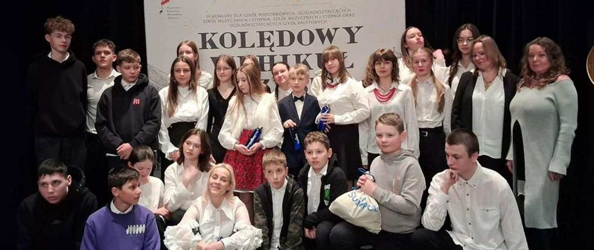 Młodzież z zespołów instrumentalno0wokalnych i nauczyciele na wspólnej fotografii.
