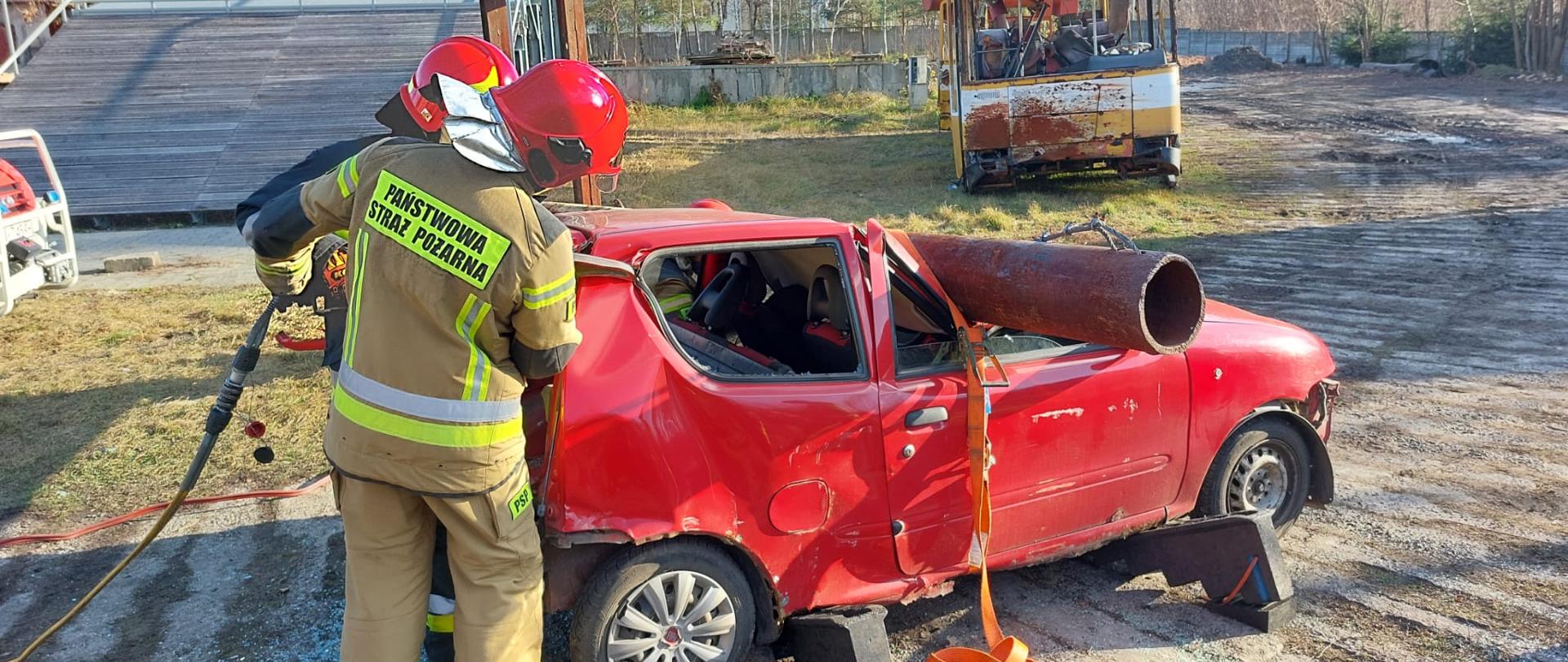 Strażak przecina słupek C przy pomocy nożyc hydraulicznych