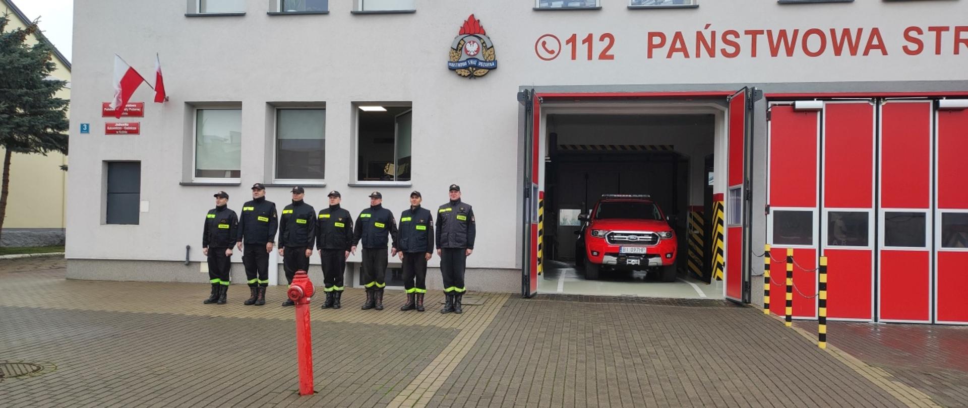 Na zdjęciu widać zmianę służbową śpiewająca hymn przed komenda PSP w Kolnie.