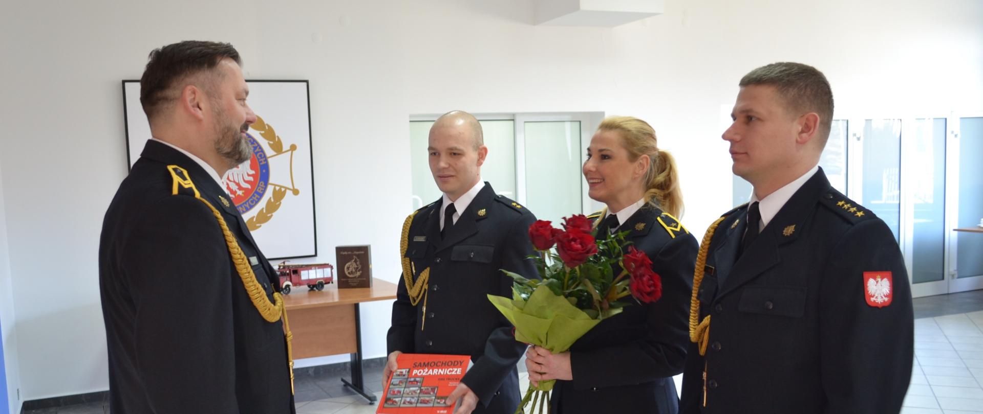 Strażacy wręczają kwiaty i pamiątkowe gadżety strażakowi "emerytowi"