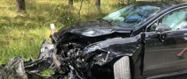 Zderzenie trzech samochodów osobowych na drodze nr DW 201 - rozbity pojazd osobowy koloru czarnego, częściowo stoi na poboczu drogi.