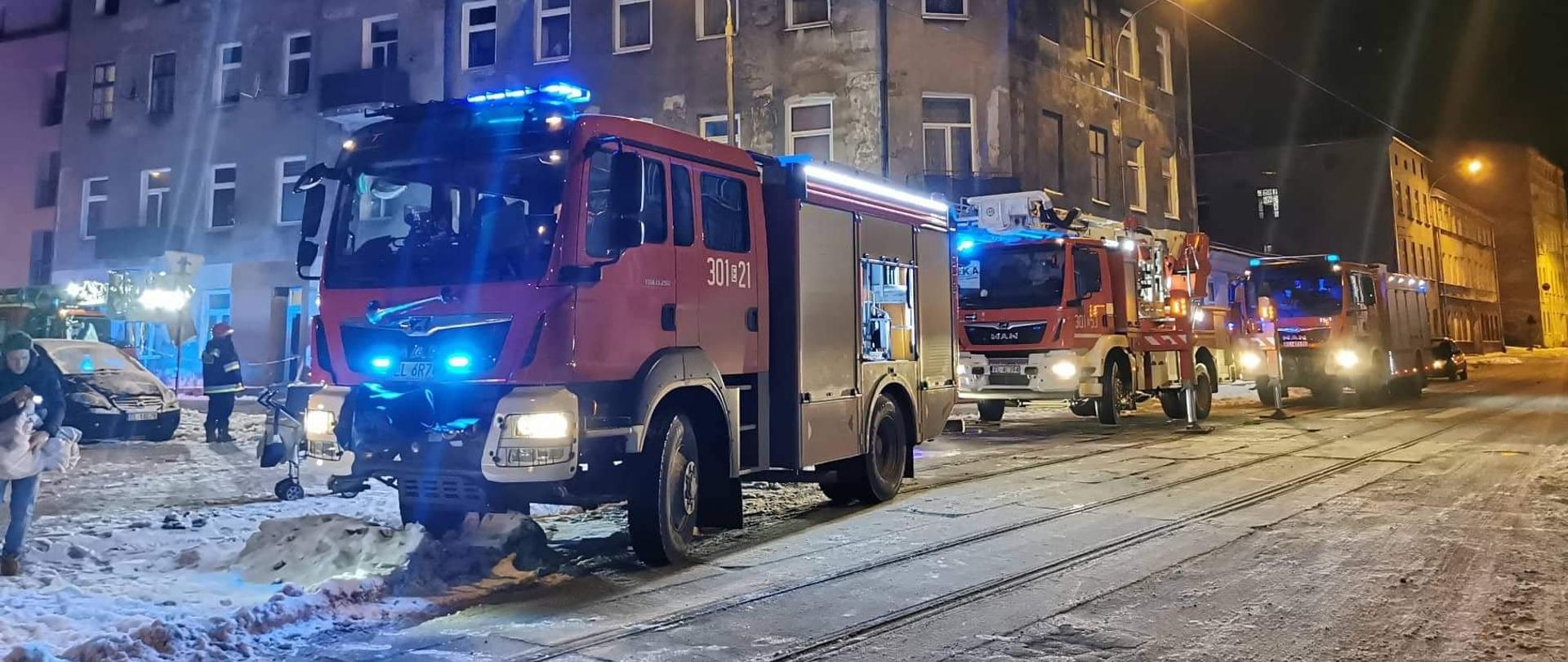 Na zdjęciu trzy samochody pożarnicze w tle kamienica