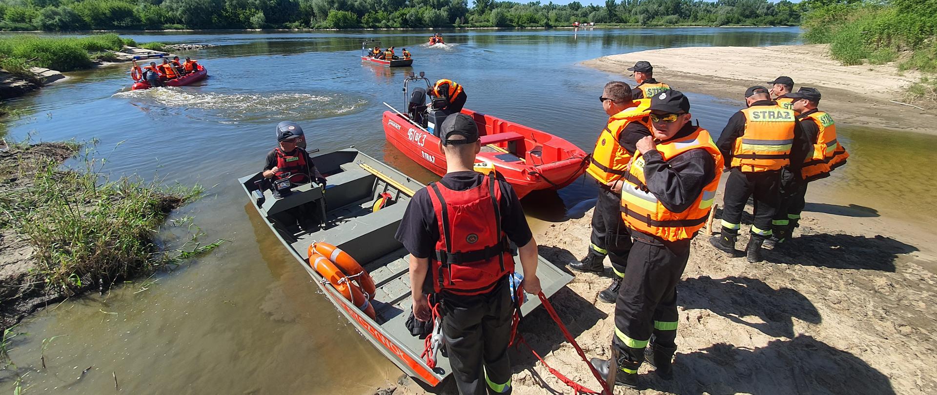 strażacy wchodzący na łodzie przed wypłynięciem na Wisłę