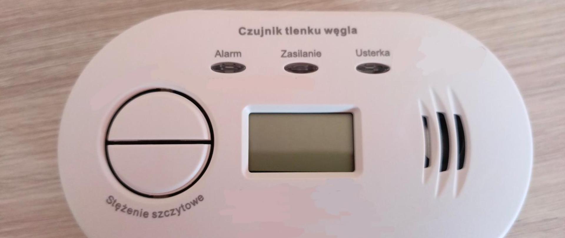 Czujnik tlenku węgla w kolorze białym na drewnianym blacie.