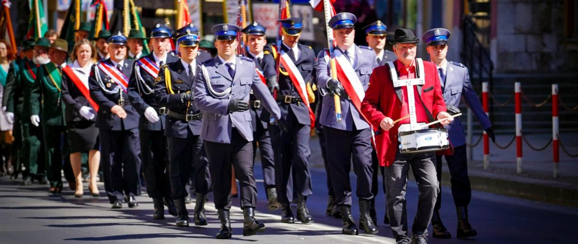 Zdjęcie przedstawia przemarsz pocztów sztandarowych przez miasto.