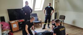 3 strażaków zdają egzamin praktyczny, 2 strażaków w komisji nadzoruje przebieg egzaminu