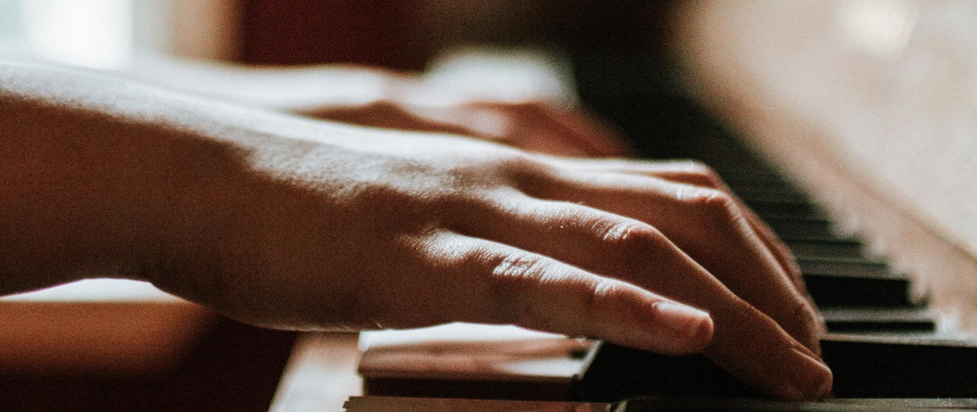zdjęcie przedstawiające dłonie na klawiaturze fortepianu