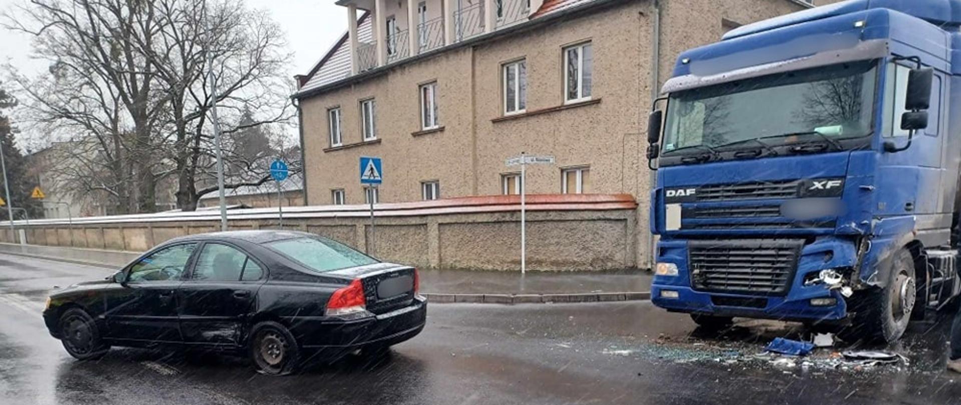 Samochód osobowy na środku skrzyżowania, po lewej pojazd ciężarowy