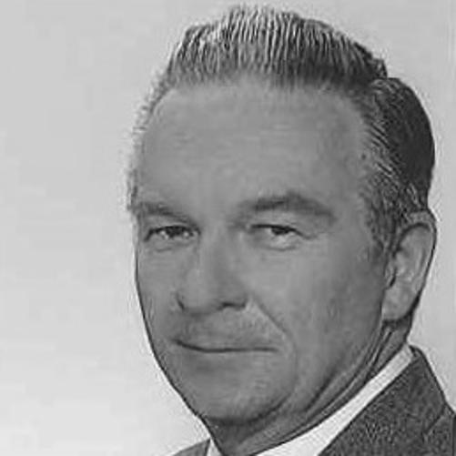 zdjęcie czarno białe przedstawia mężczyznę w garniturze w białej koszuli i z krawatem, 