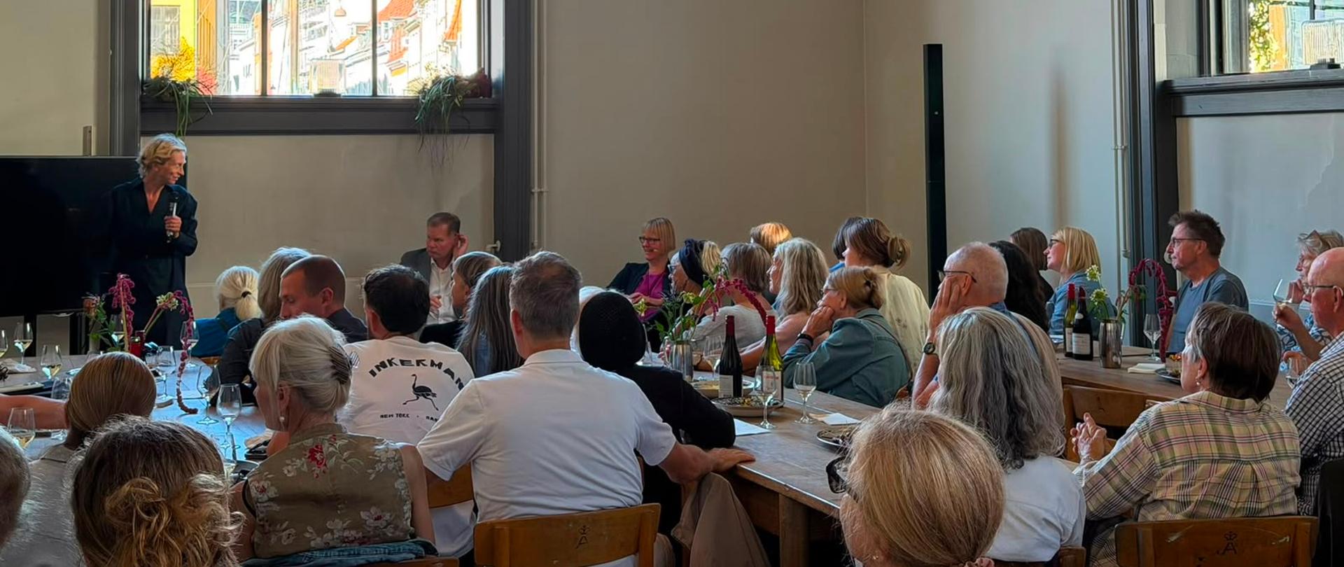 A discussion panel featuring three speakers in conversation before an audience during an event at Kunsthal Charlottenborg.