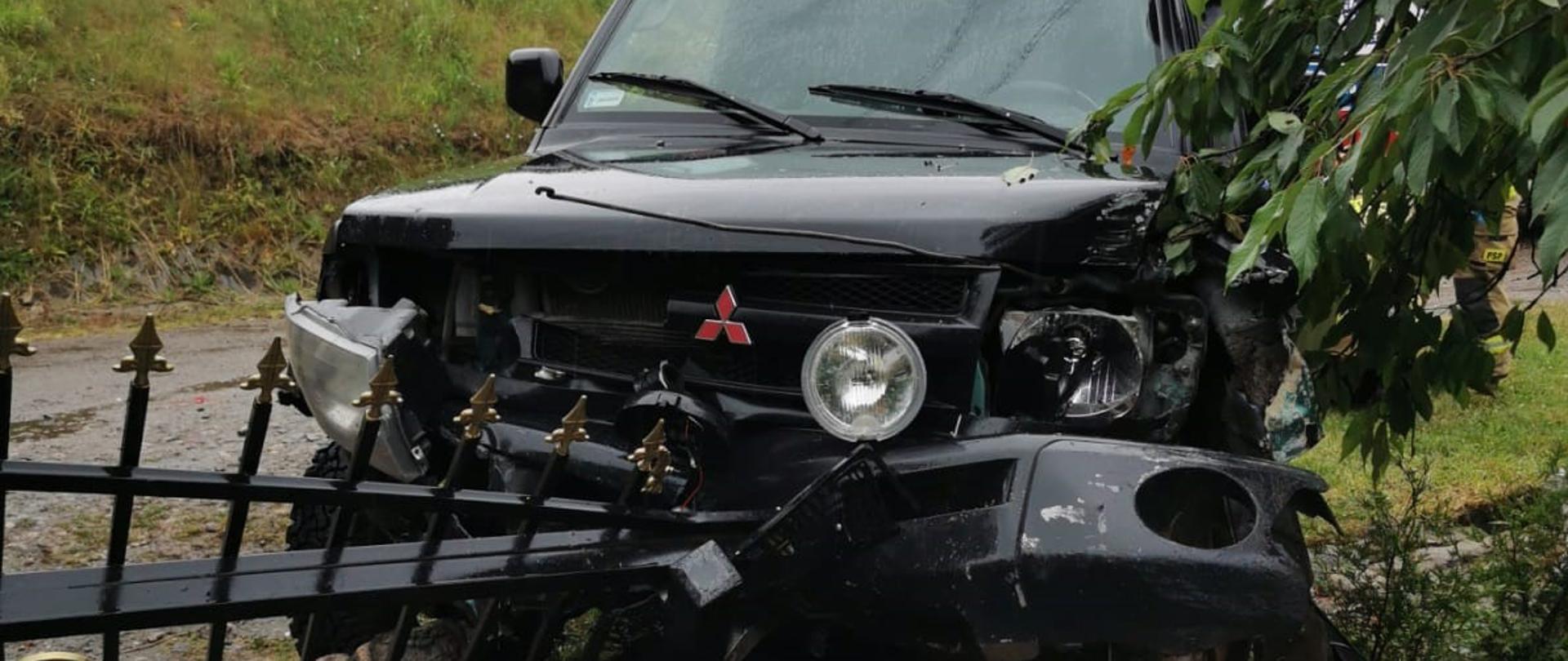 Fotografia przedstawia uszkodzony pojazd po uderzeniu w ogrodzenie.