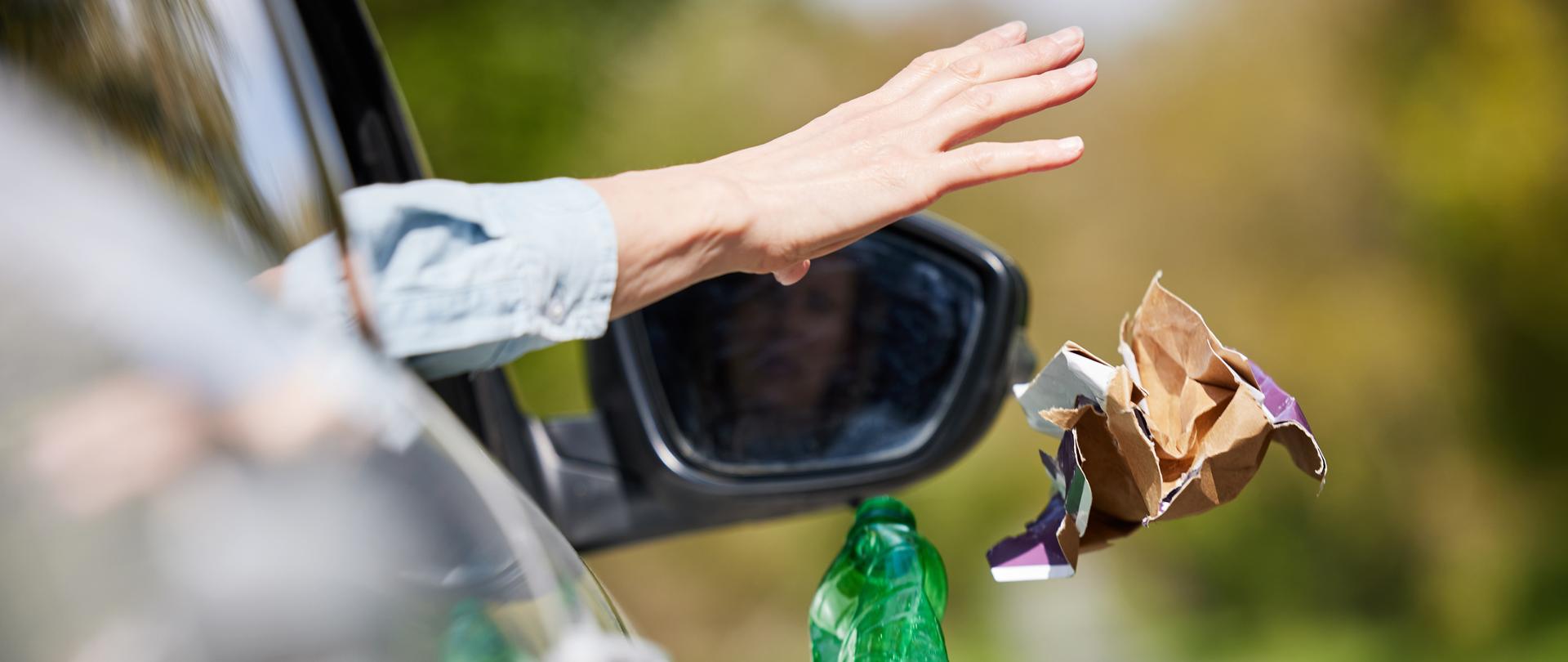 mężczyzna wyrzuca śmieci z samochodu