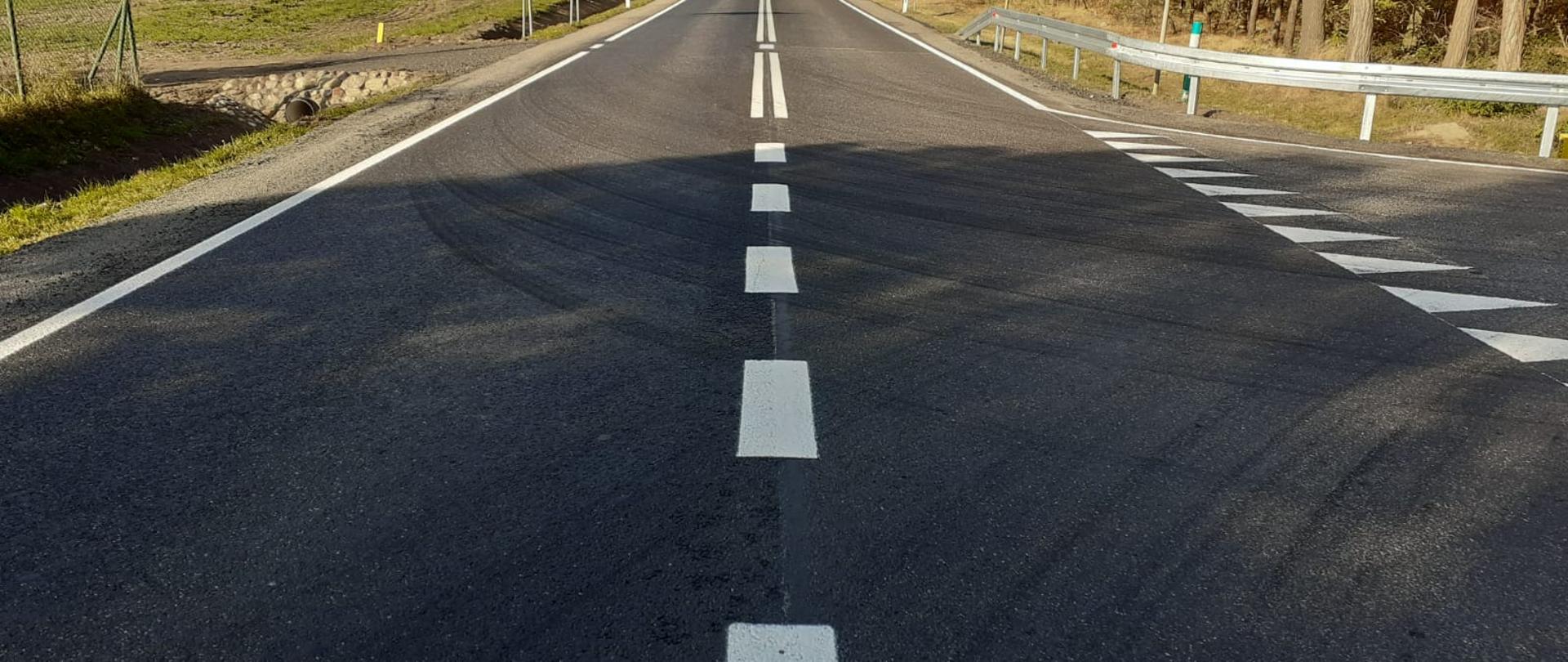 Widok jezdni z wymalowanym oznakowaniem poziomym tj. po lewej strony linia ciągła, po środku linia przerywana a po prawej widoczny wyjazd z drogi podporządkowanej.