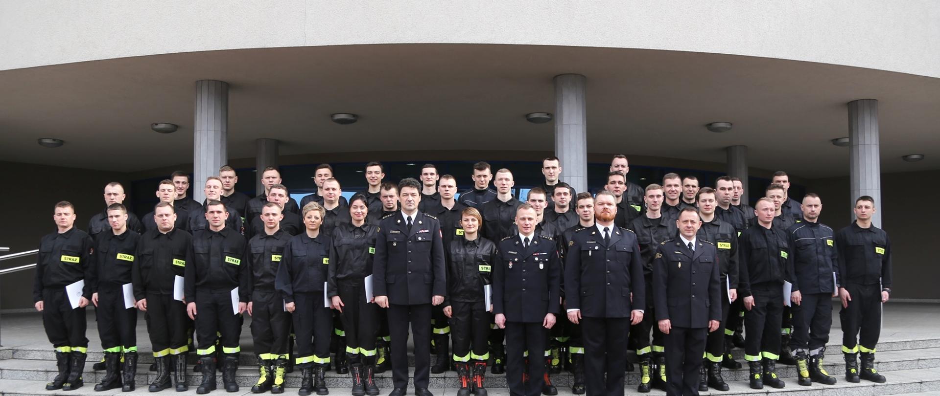 Grupowe zdjęcie uczestników szkolenia (40 osób, w tym trzy kobiety) w towarzystwie Komendanta Centralnej Szkoły PSP, Zastępcy Komendanta CS PSP oraz dwóch oficerów CS PSP