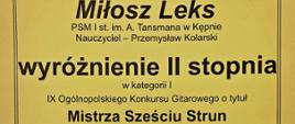 Dyplom na żółtym tle w czarnym obramowaniu. Niemal cały dyplom zajmuje tekst w czarnym kolorze. Od góry napis dyplom, imię i nazwisko ucznia, nazwa szkoły, nauczyciel, napis wyróżnienie II stopnia, kategoria, nazwa konkursu, patronat honorowy, data i miejsce konkursu oraz skład jury wraz z podpisami jurorów. Na dole grafika - 3 kolorowe zdjęcia w rzędzie - różne ujęcia gitary (zbliżenie na gryf, pudło rezonansowe i struny). Zaraz nad grafiką kilka logotypów. 
