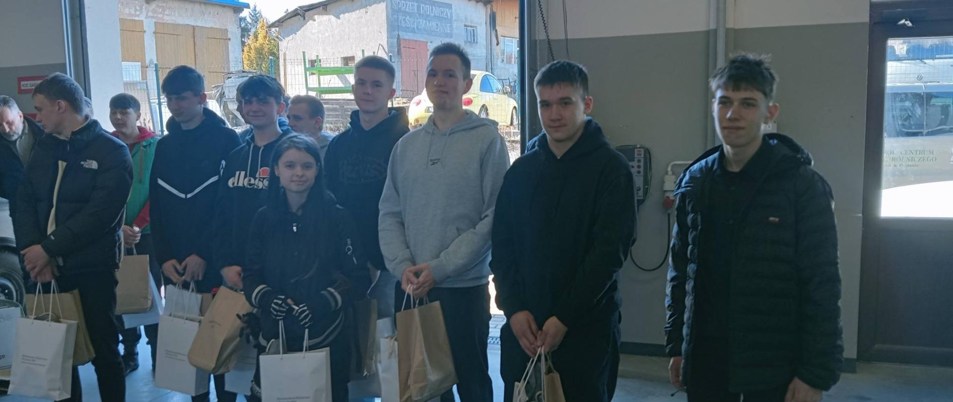 Uczniowie pozują do zdjęcia, stoją z nagrodami i upominkami 