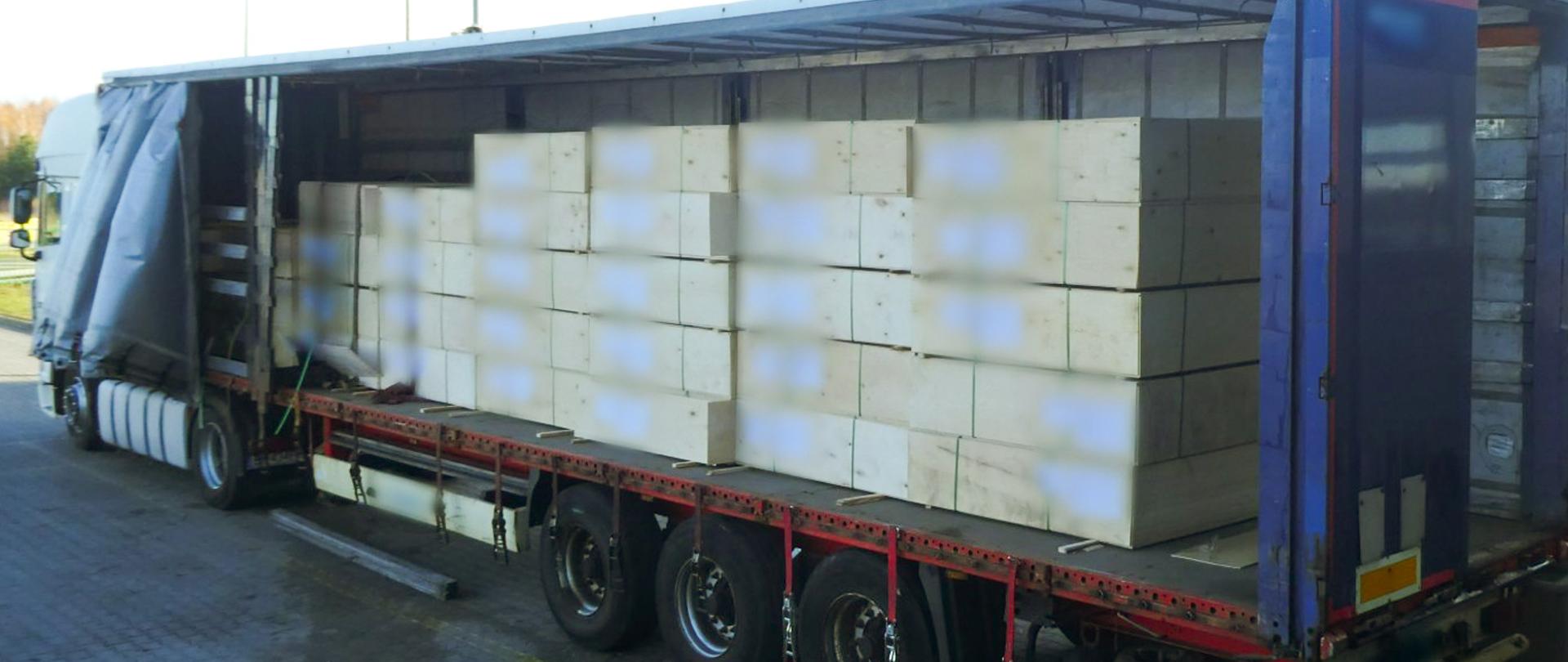 Otwarta naczepa samochodu ciężarowego, w środku palety sklejki.