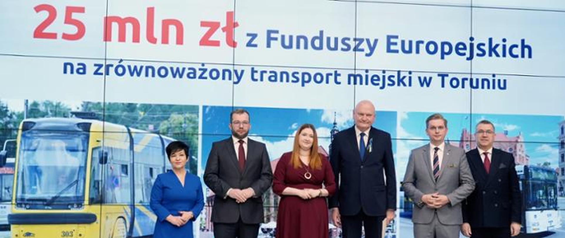 Dwie kobiety i czterech mężczyzn stojących na tle planszy