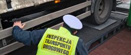 Inspektor w kamizelce odblaskowej zagląda pod przyczepę
