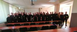 grupa strażaków w umundurowaniu koszarowym pozująca do zdjęcia w sali wykładowej