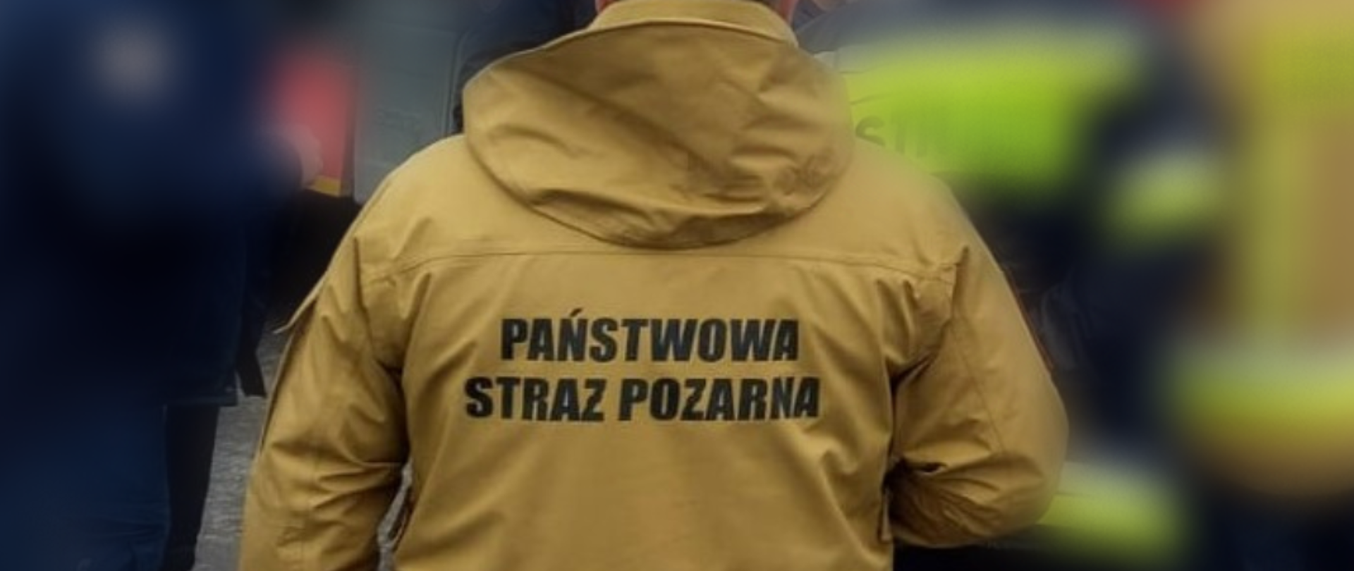 Widok z tyłu na strażaka PSP ubranego w kurtkę przeciwdeszczową z napisem PAŃSTWOWA STRAŻ POŻARNA