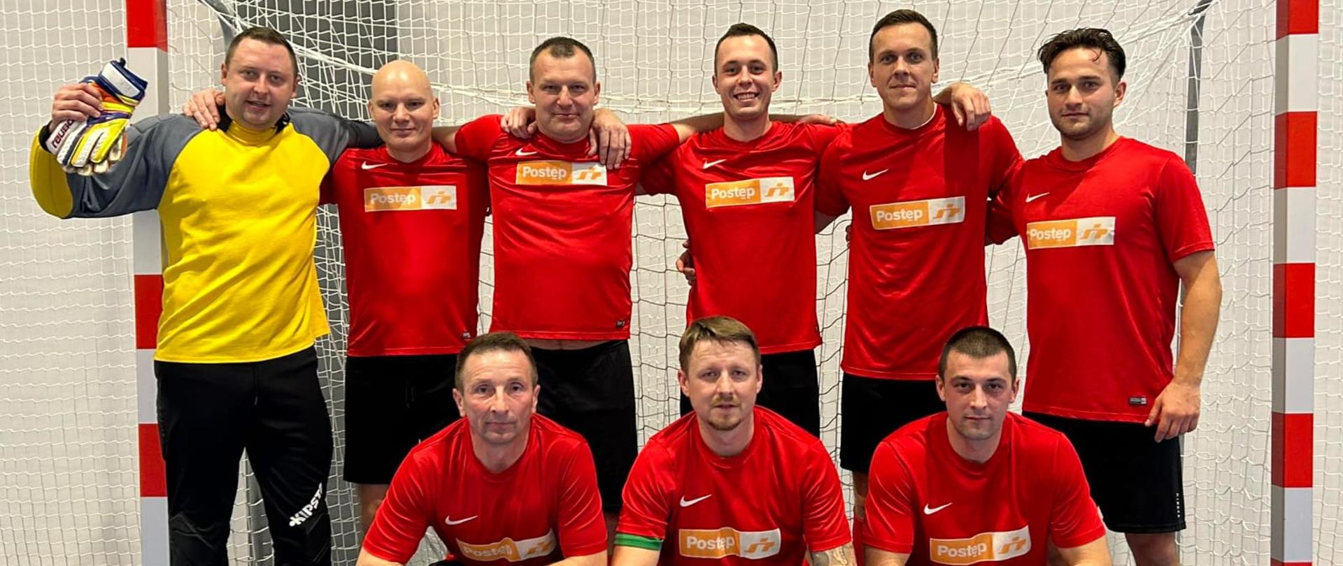 Zawodnicy komendy w czerwonych koszulkach na tle bramki, grupowo