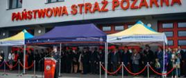 Goście oraz strażacy na tle budynku komendy podczas uroczystości