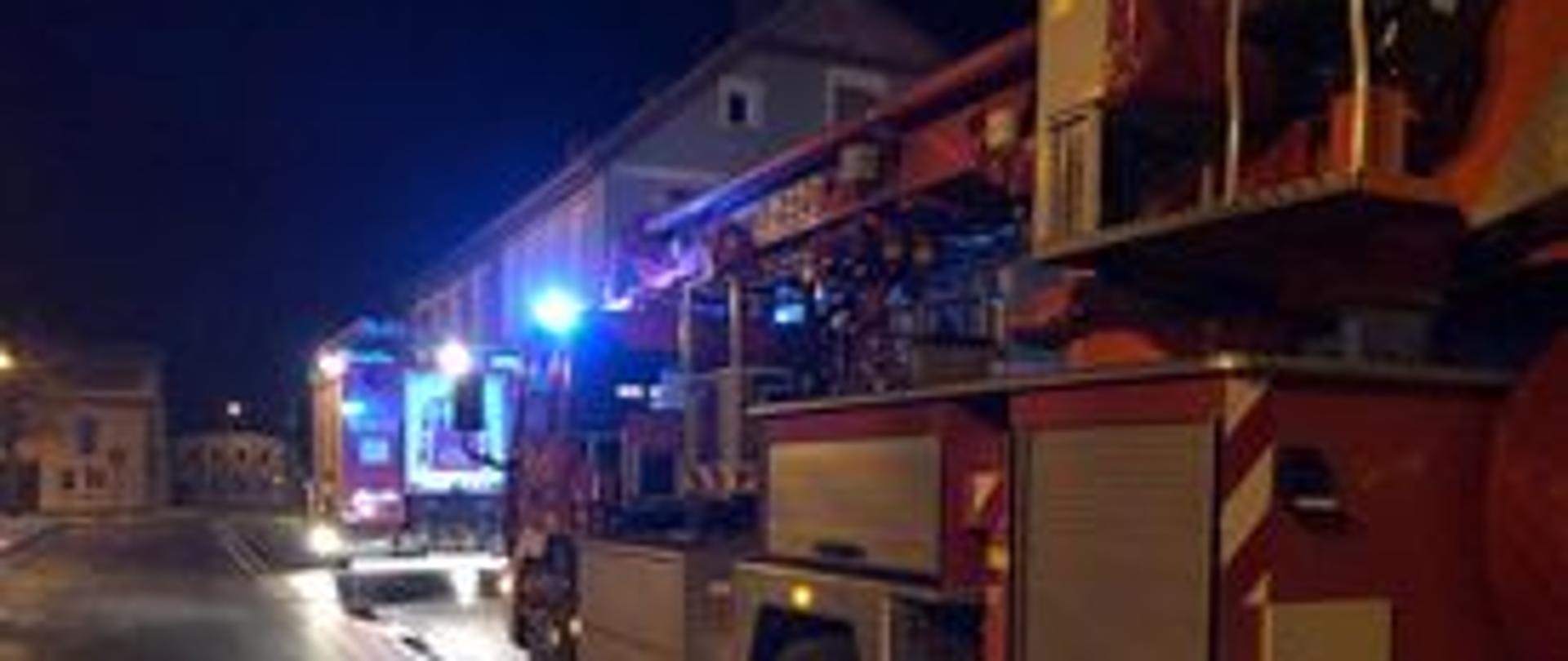 Zdjęcie przedstawia pojazd pożarniczy SHD-25 stojący na jezdni z włączonymi światłami alarmowymi