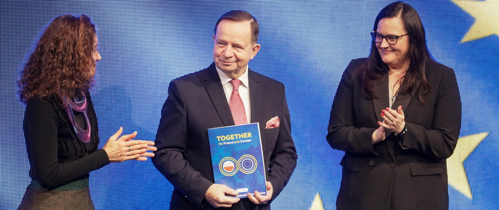 Trzy osoby na scenie. Od lewej dyrektor Cinzia Masina, marszałek Władysław Ortyl i wiceminister Małgorzata Jarosińska-Jedynak. Mężczyzna trzyma w ręku dokument.