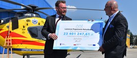 Minister zdrowia Łukasz Szumowski przekazuje symboliczny czek dyrektorowi Lotniczego Pogotowia Ratunkowego Robertowi Gałązkowskiemu podczas briefingu prasowego.