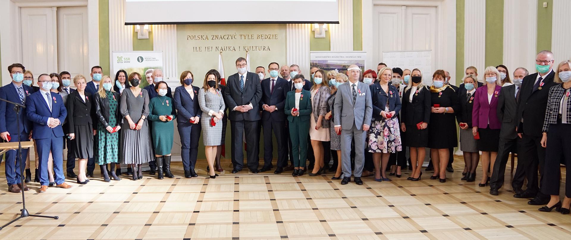 Minister Szymon Giżyński stojący wśród odznaczonych nauczycieli