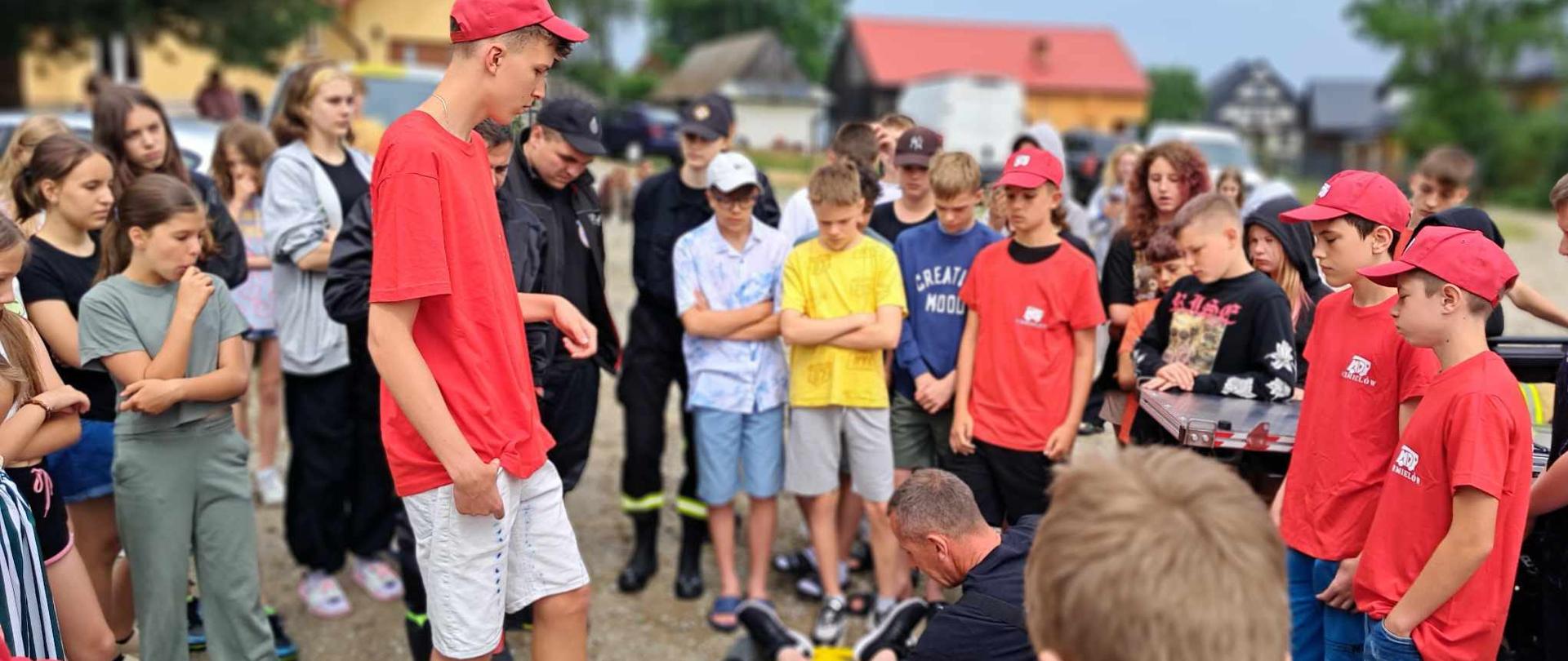 Druhowie MDP zebrani na instruktarzu udzielania pierwszej pomocy. Plac przed miejscem zakwaterowania.