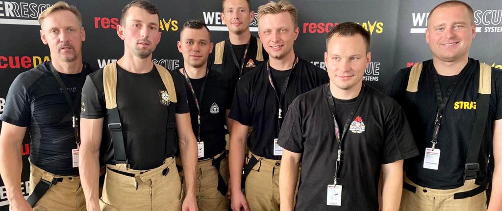 Zdjęcie przedstawia ratowników z JRG nr 1 w Kielcach, którzy brali udział w warsztatach Rescue Days. Pl na tle ścianki.