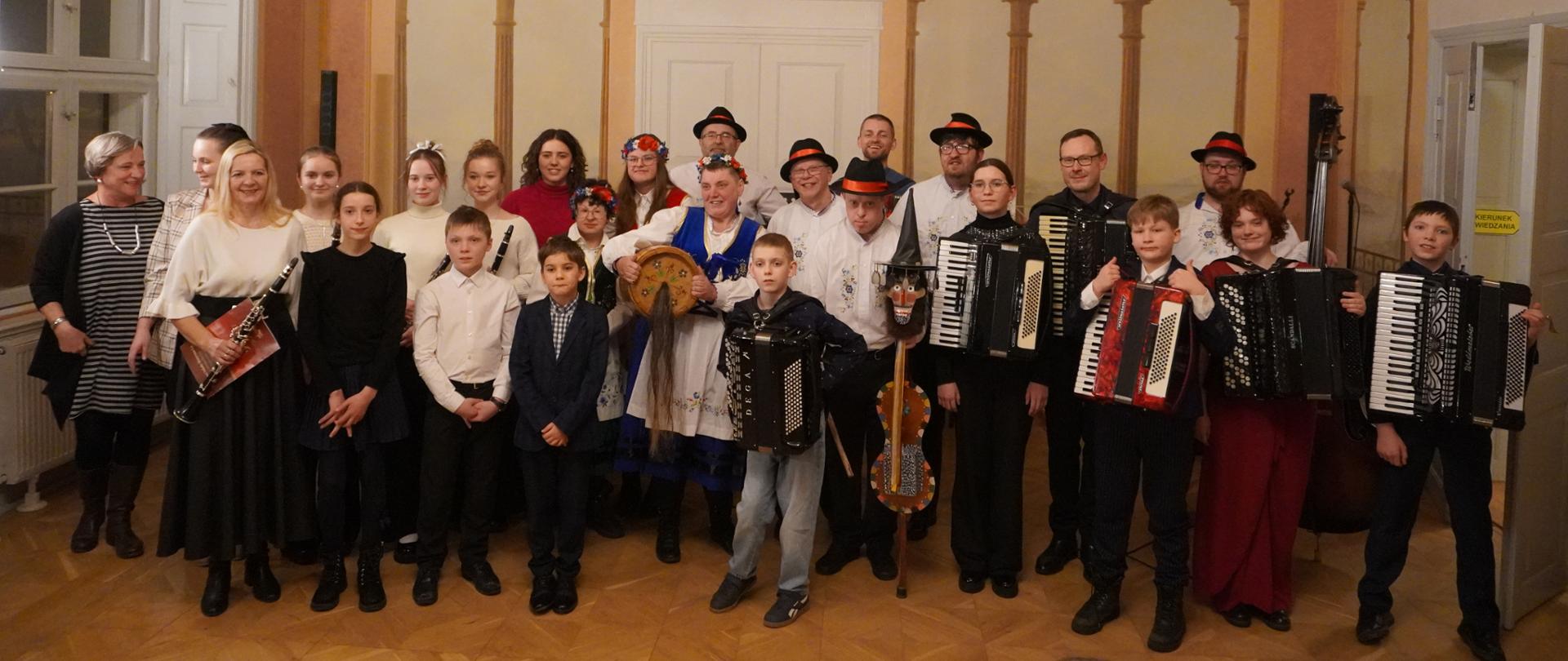 W Sali Balowej wejherowskiego muzeum pozują wszyscy wykonawcy Koncertu Zimowego. Stoją wraz ze swoimi instrumentami.