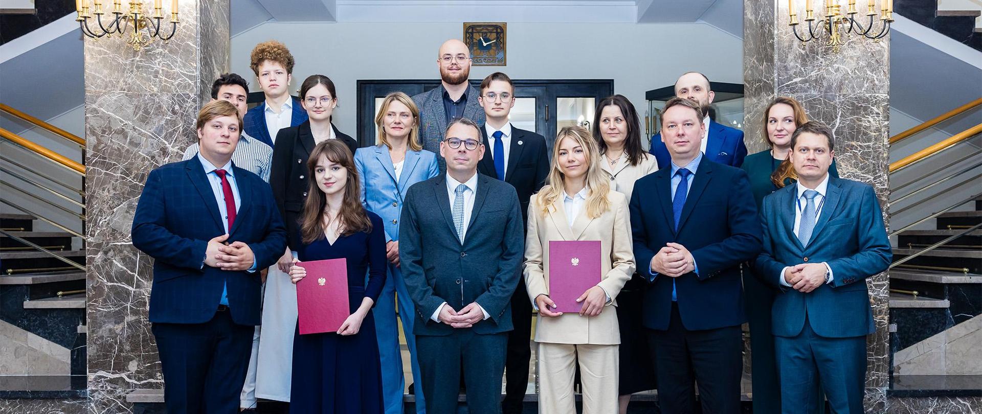 Wiceminister Jakub Wiśniewski oraz wiceminister Marek Krawczyk wręcza nominacje młodzieżowym delegatkom do ONZ