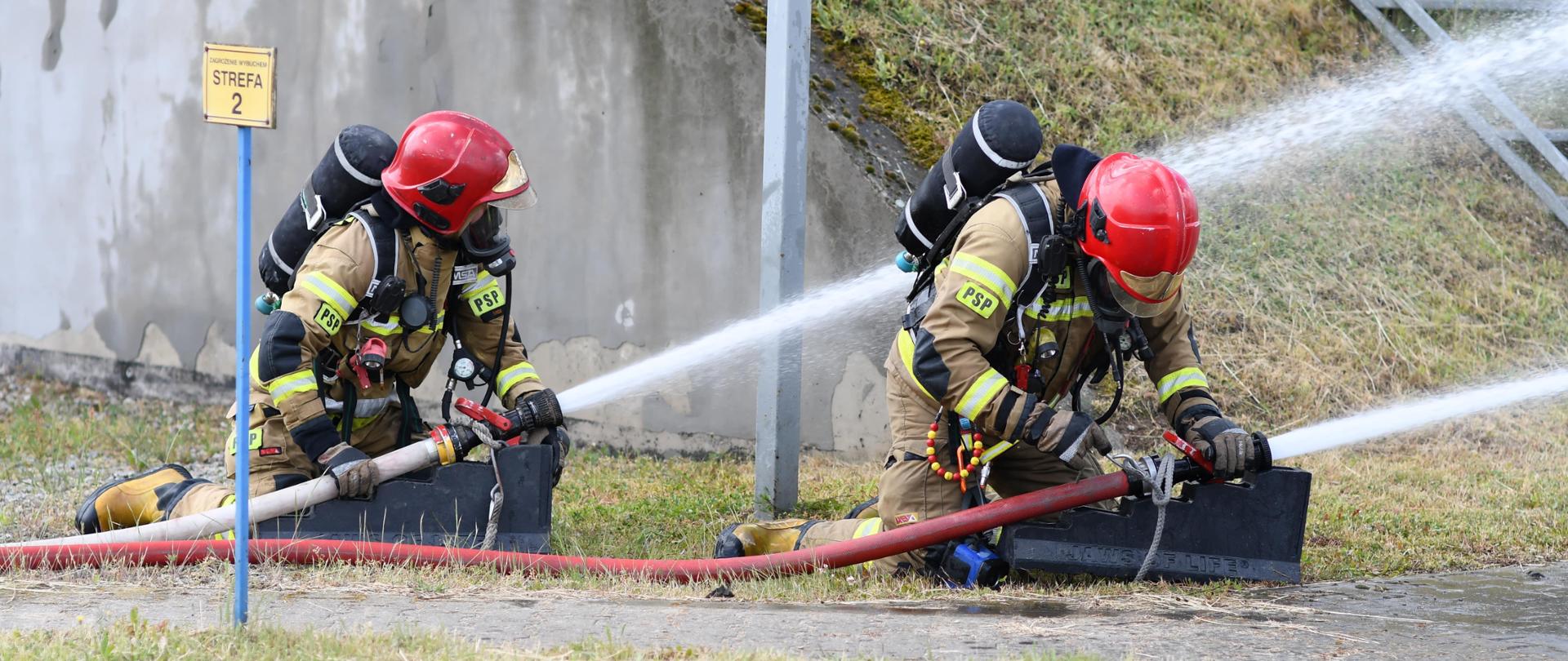 Strażacy przygotowujące prądy wody do podania na autocysternę