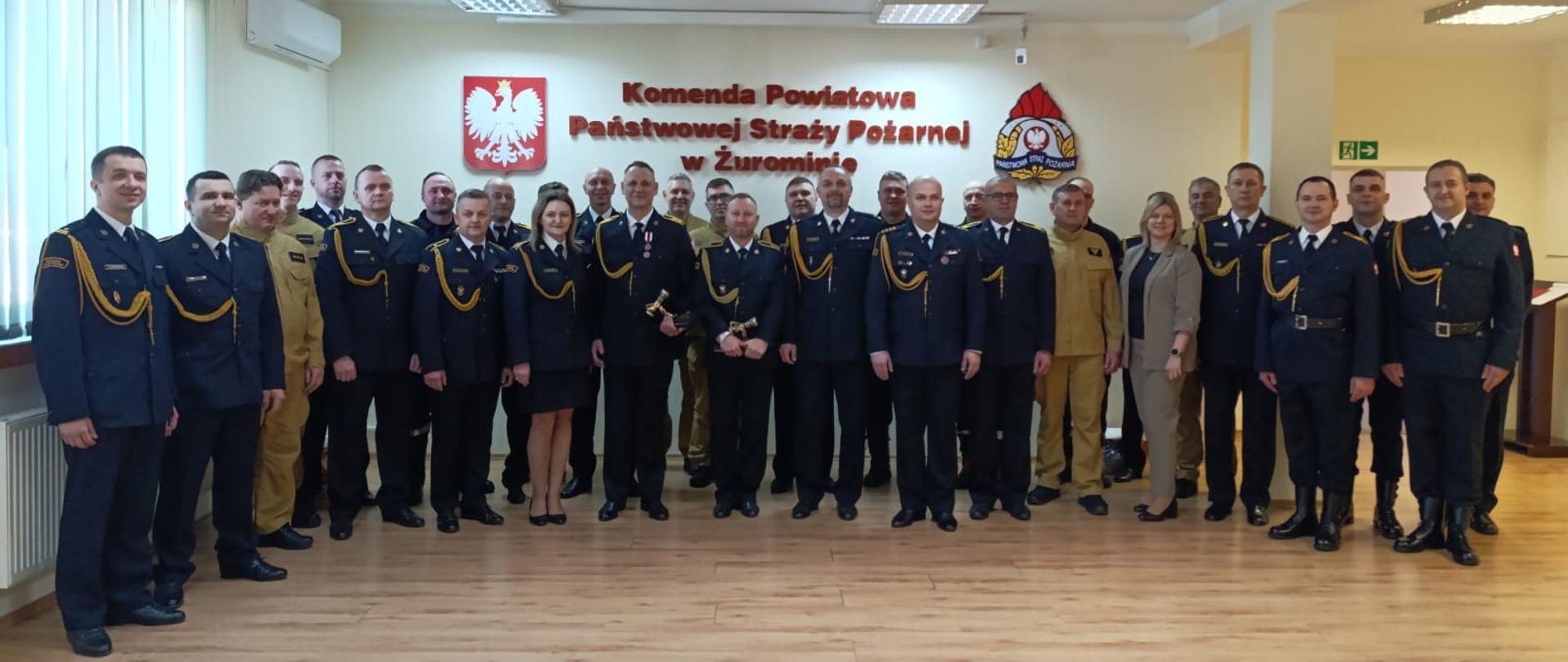 Na zdjęciach przedstawiono uroczyste pożegnanie funkcjonariuszy odchodzących na emeryturę w Komendzie Powiatowej Państwowej Straży Pożarnej w Żurominie. Podczas zbiórki komendant wręczył odchodzącemu strażakowi pamiątkowe dokumenty w obecności kolegów z jednostki oraz zaproszonych gości.