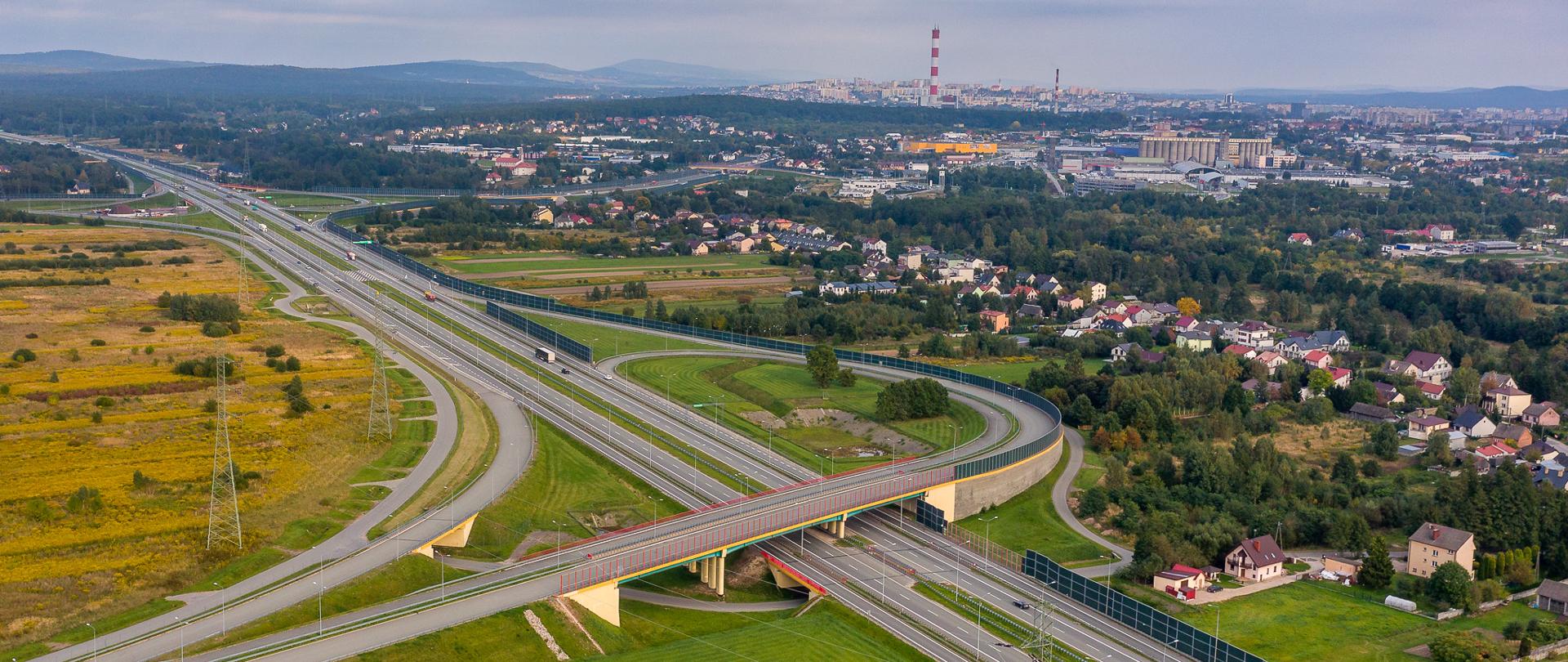 S7 Kielce Zachód - węzeł drogowy na pierwszym planie, na drugim planie panorama miasta (zdjęcie lotnicze) 