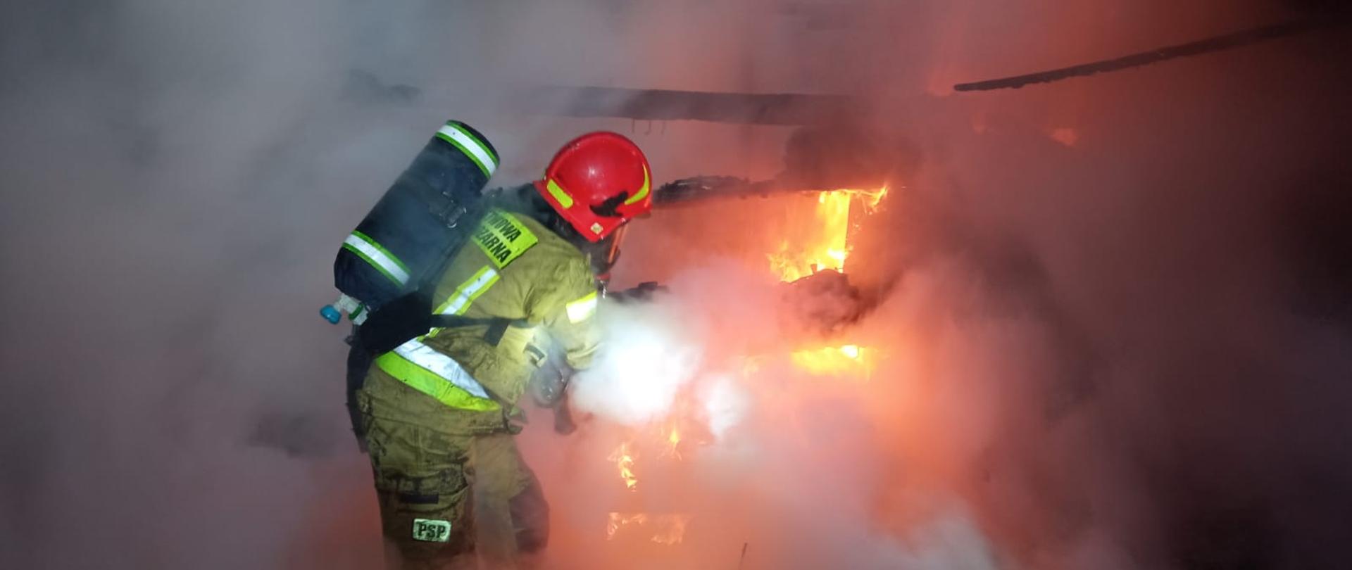 Zdjecie przedstawia strażaka podczas gaszenia pożaru
