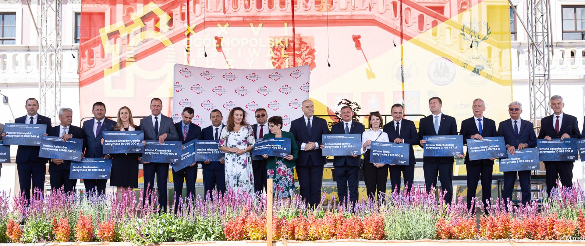 Wicepremier Jacek Sasin stoi w otoczeniu prezydenta Zamościa i innych uczestników spotkania. 