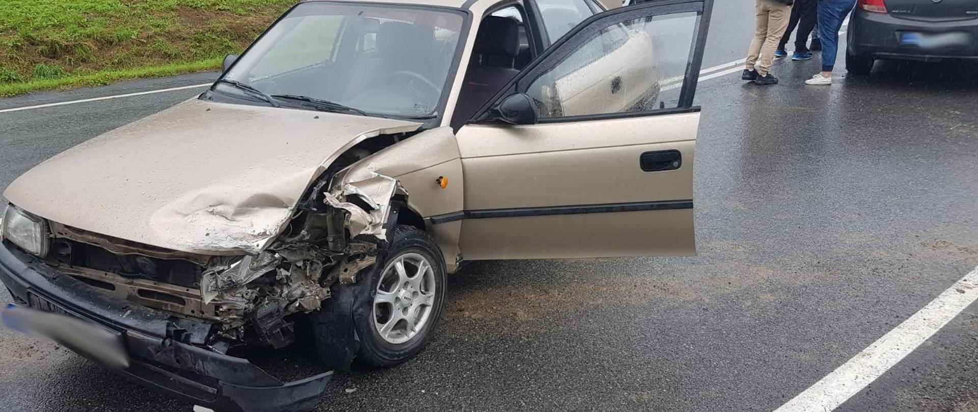 Samochód osobowy z rozbitym przodem na drodze.