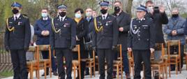 Na pierwszym planie funkcjonariusze w mundurach galowych podczas mszy polowej z okazji Dnia Strażaka. Na planie drugim przedstawiciele władz powiatu i gmin w powiecie brzezińskim.
